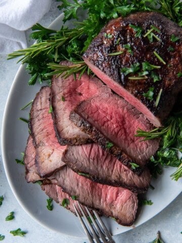 Overhead view of air fryer roast beef half sliced on a serving plate.