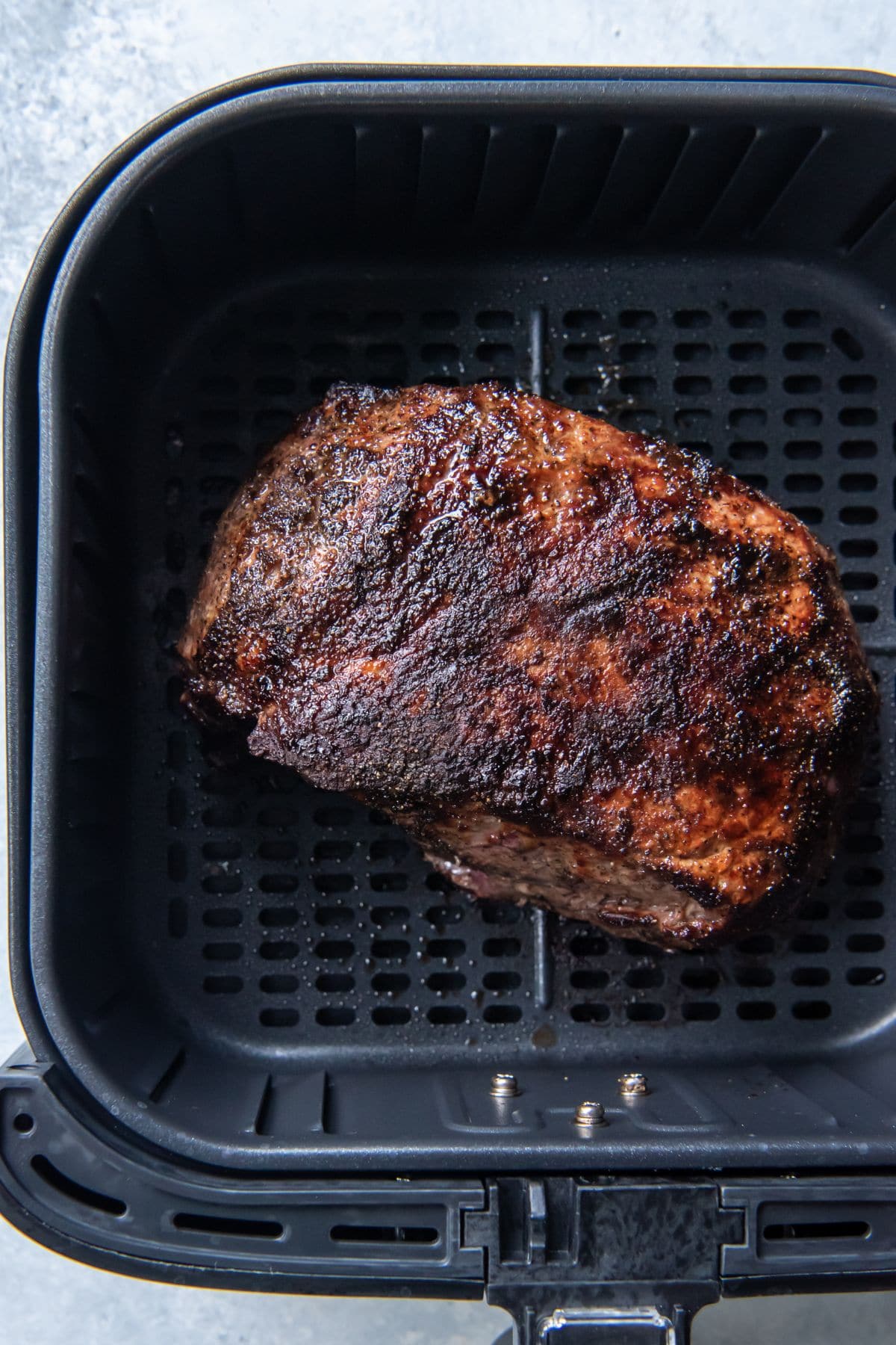 Fully cooked and roasted roast beef in an air fryer basket.