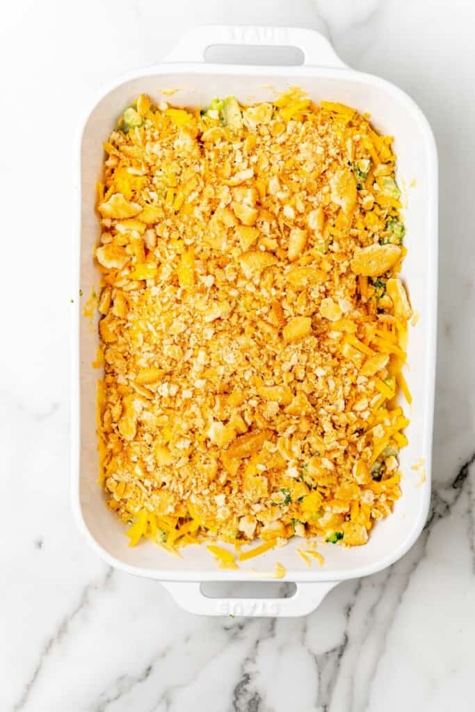 Crushed ritz crackers spread over broccoli and cheese mixture in a casserole dish.