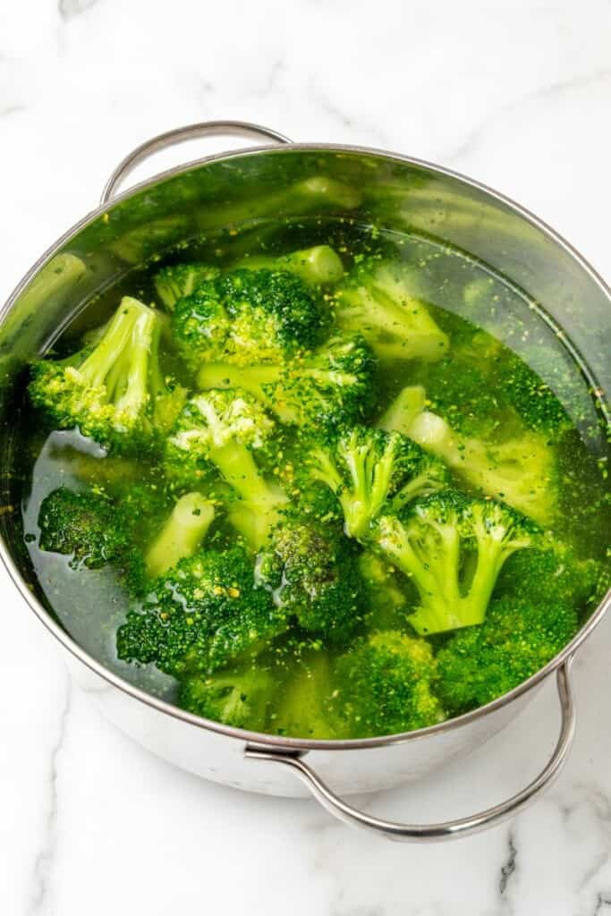 Blanching frozen broccoli in salted water.