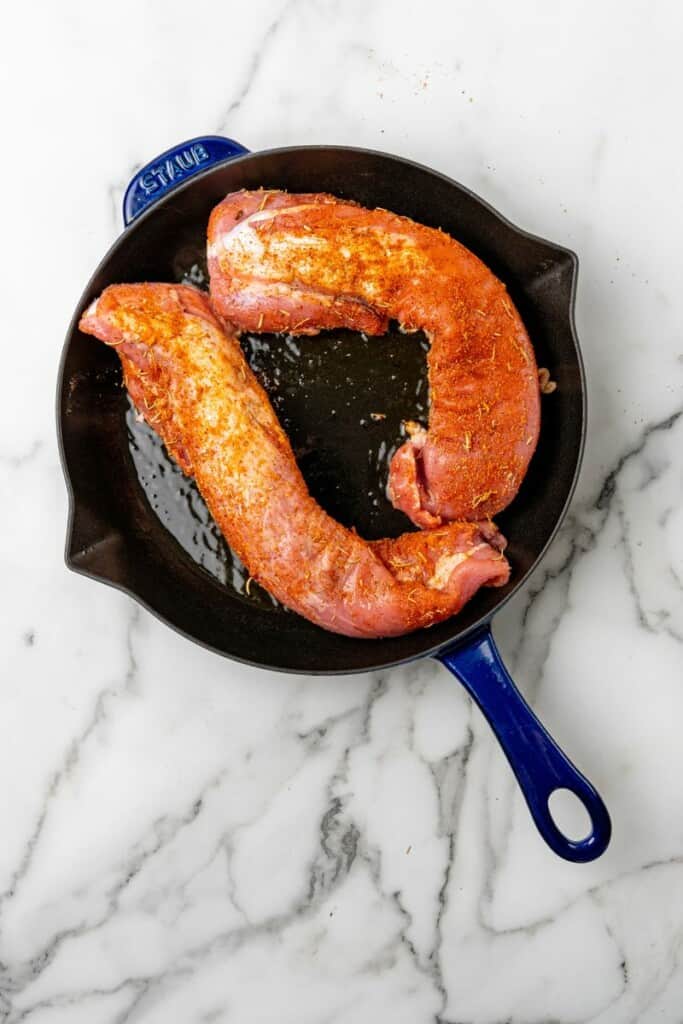 Seasoned pork tenderloin in a cast iron skillet.