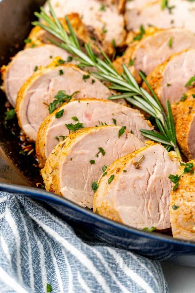 Close up view of slices of pork tenderloin in a cast iron skillet.
