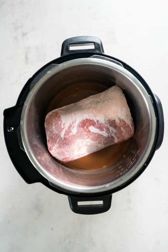 Placing a frozen pork loin in the instant pot.