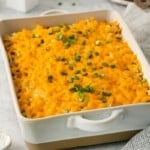 A serving dish of hashbrown hamburger casserole topped with green onions.