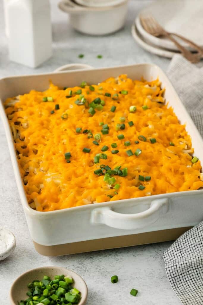 A serving dish of hashbrown hamburger casserole topped with green onions.