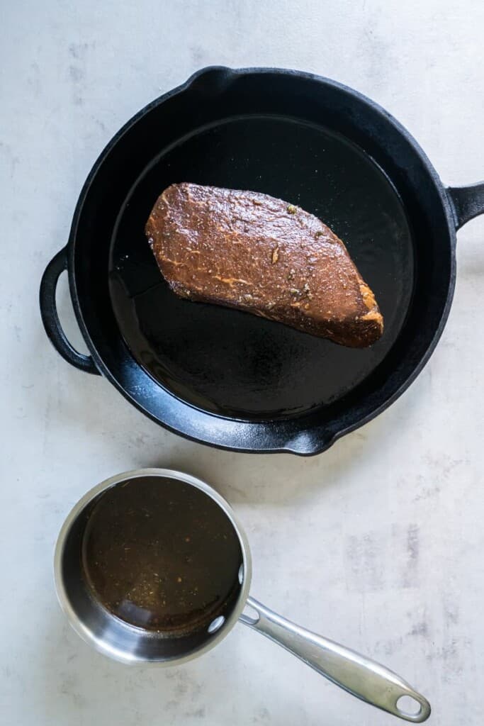 Marinated London Broil in a skillet. Marinade in a small saucepan.