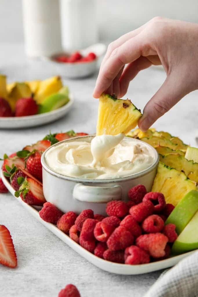 Dipping pineapple into marshmallow dip for fruit.