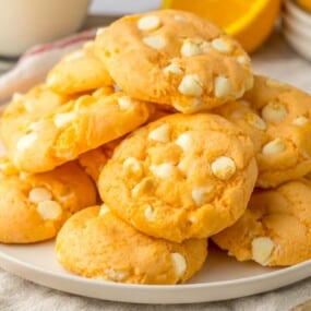Orange creamsicle cookies with white chocolate chips stacked on top of each other