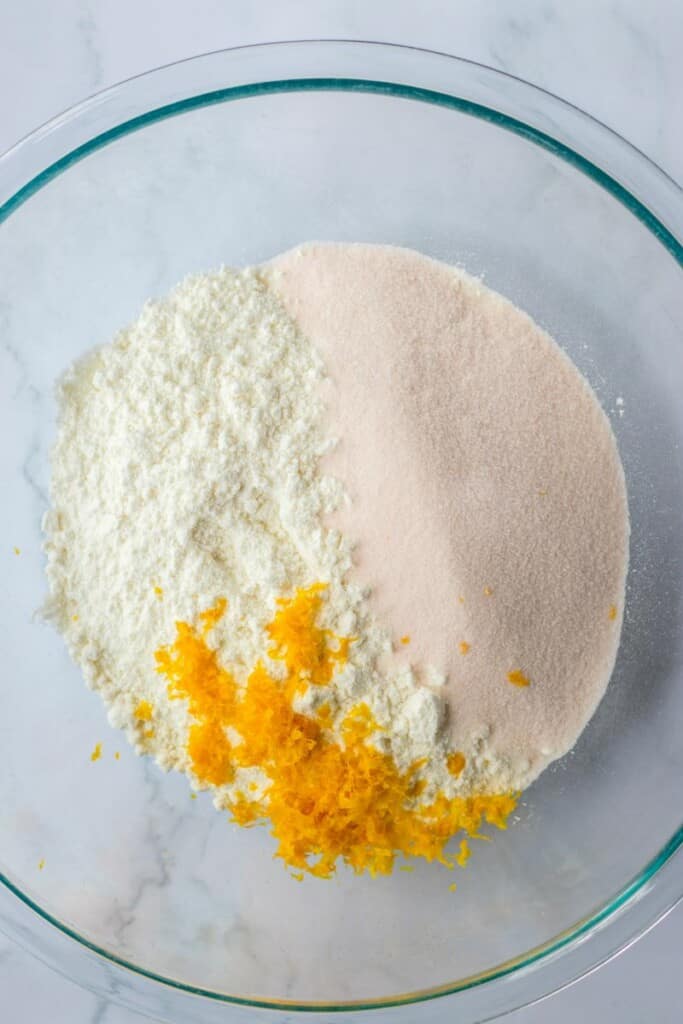 Combining cake mix, orange jello powder and orange zest in a clear mixing bowl.