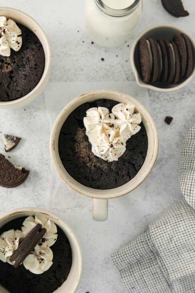 Overhead view of oreo cakes in mugs topped with whipped cream.