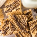 Rice Krispie Treat Squares made with peanut butter and chocolate drizzle with a glass of milk.