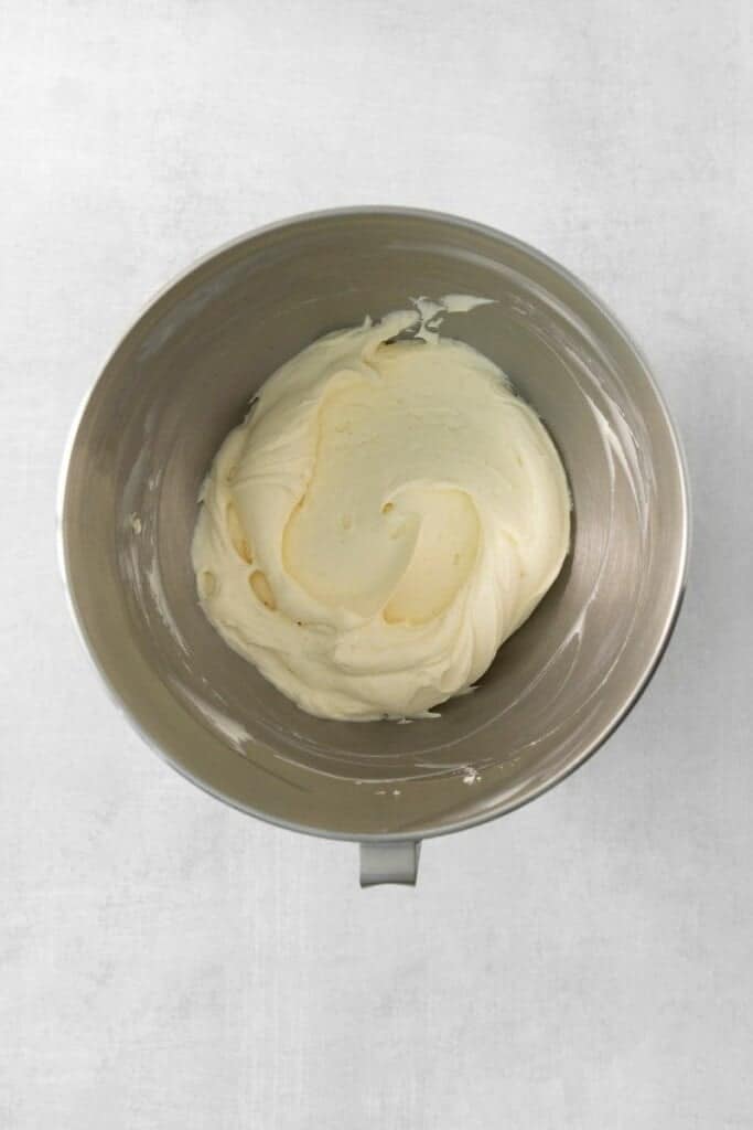 Adding cream cheese, powdered sugar and vanilla bean paste to pudding mixture in a mixing bowl.