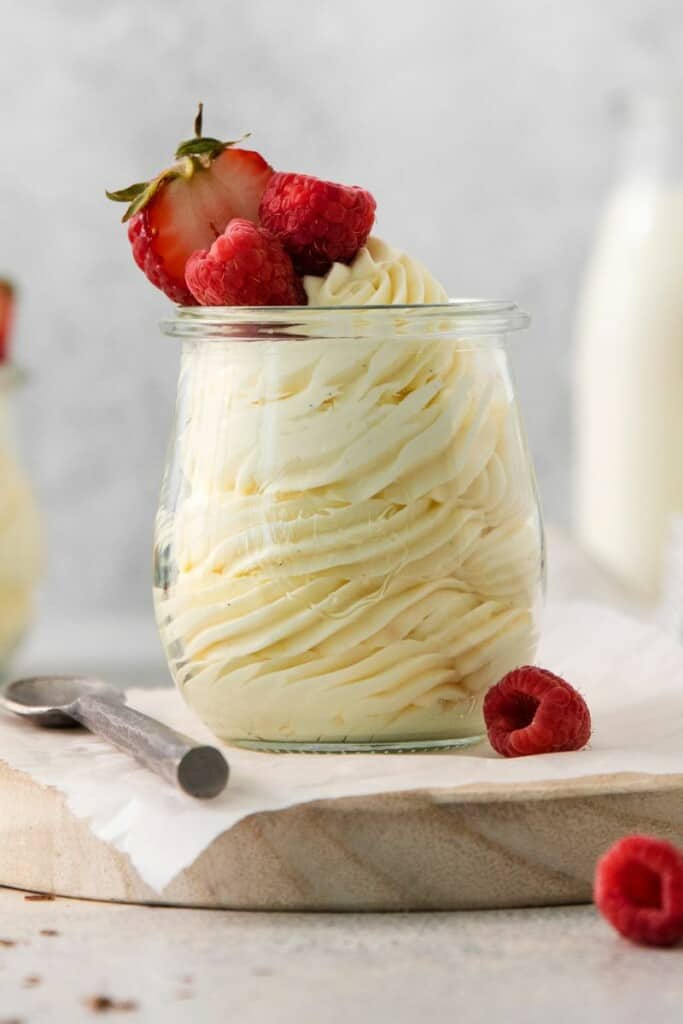 Close up view of vanilla mousse in a serving dish topped with fresh berries.