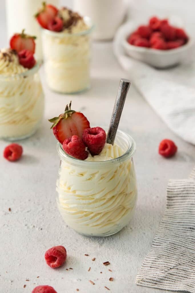 A serving bowl of vanilla mousse topped with fresh berries.