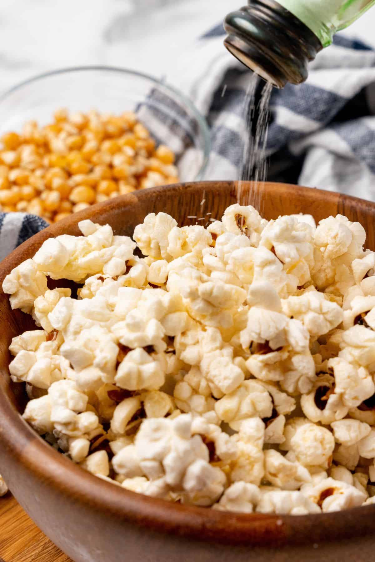 Salt being poured onto the popped air fry popcorn.
