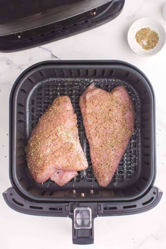 Raw turkey tenderloin in an air fryer basket about to be cooked.