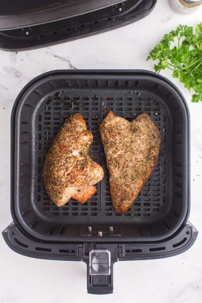 Cooked turkey tenderloin in an air fryer basket.