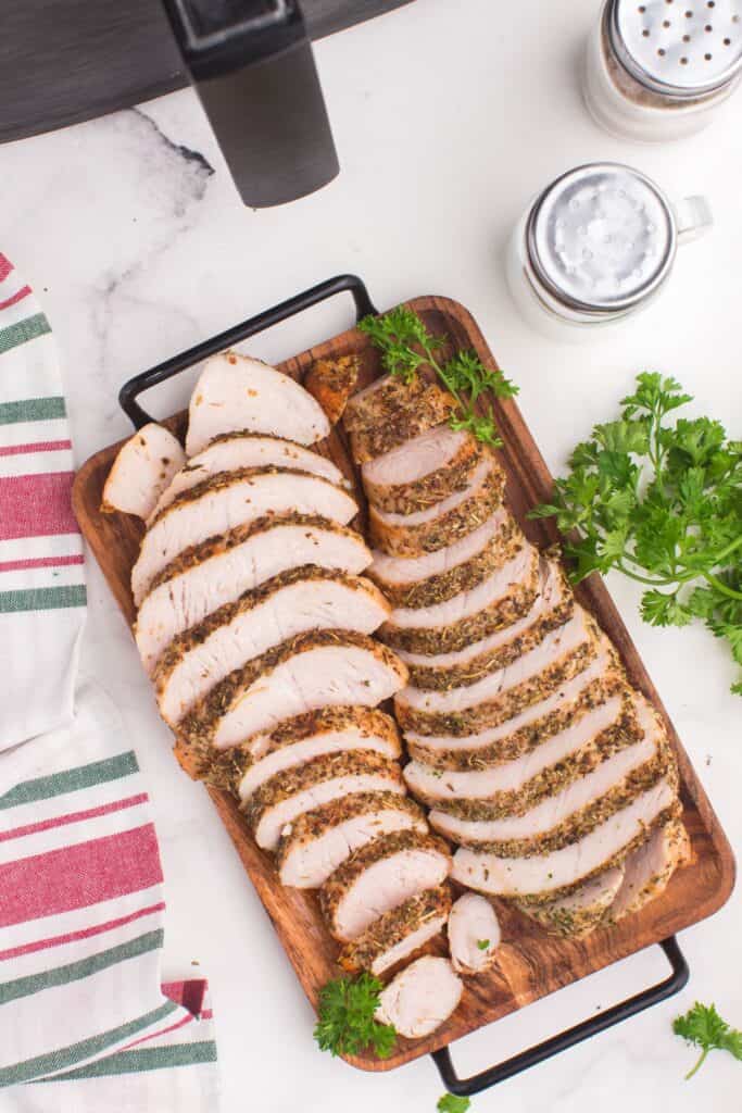 Air fryer turkey tenderloin sliced on a wooden serving platter.