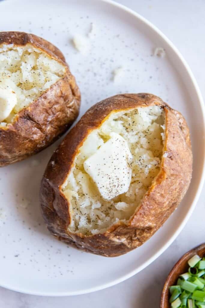 Closeup of a baked potato cut in half with butter in the middle