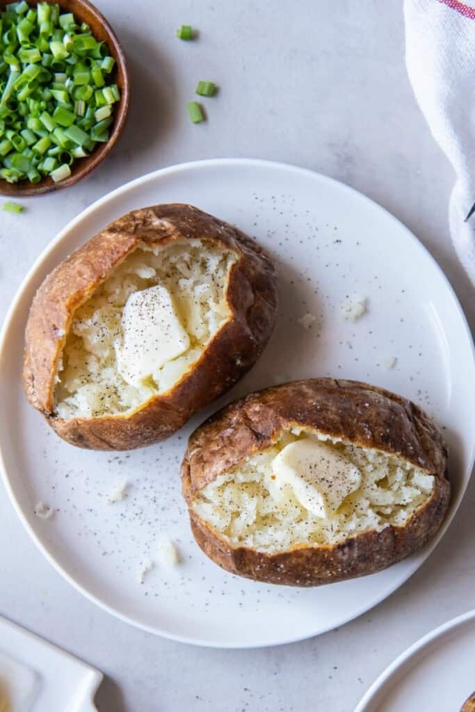 Baked potatoes on a plate with a dollop of butter in center