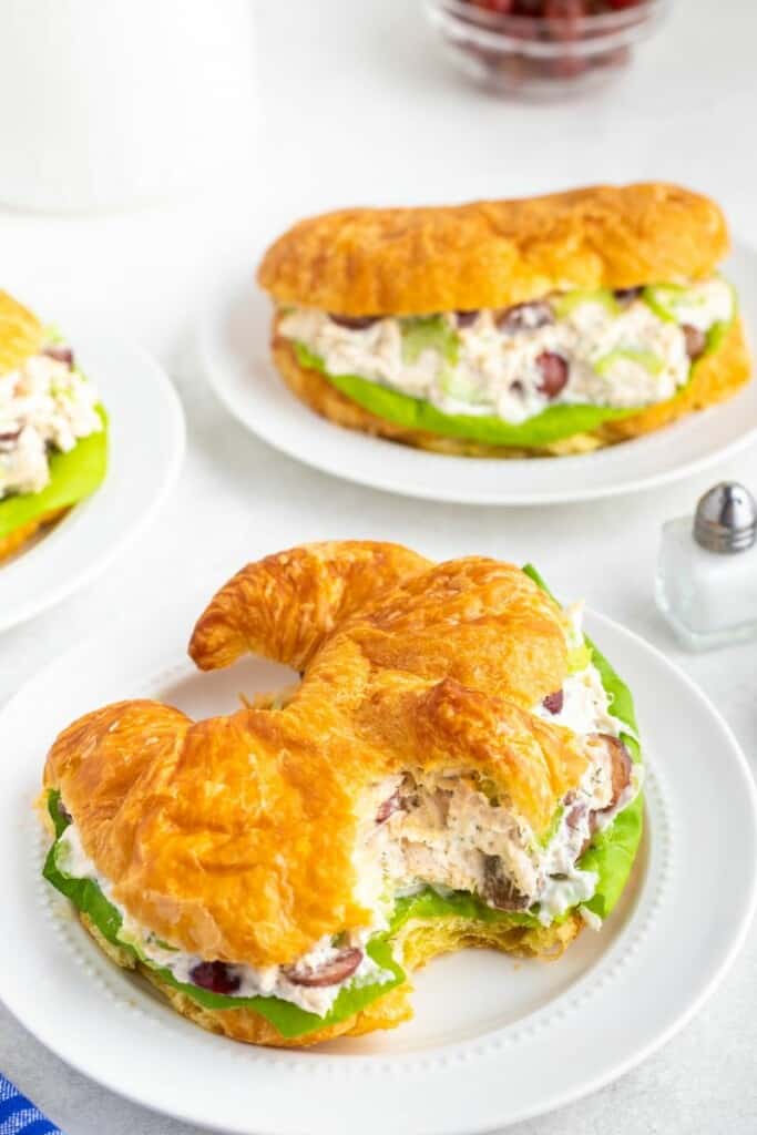 Chicken Salad being served as sandwiches with croissants on white plates.