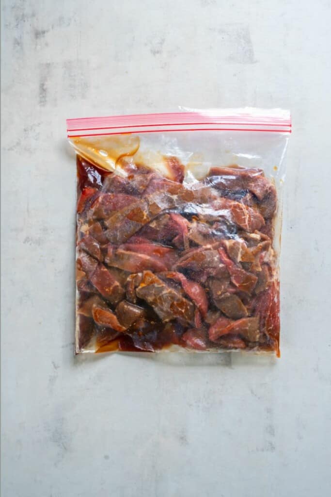 Slices of sirloin steak in a zip top bag with teriyaki sauce.