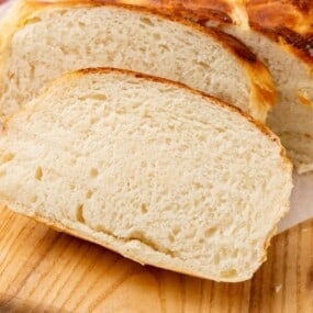 Homemade bread cut into slices on a wooden cutting board.