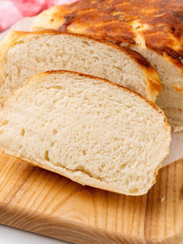 Homemade bread cut into slices on a wooden cutting board.