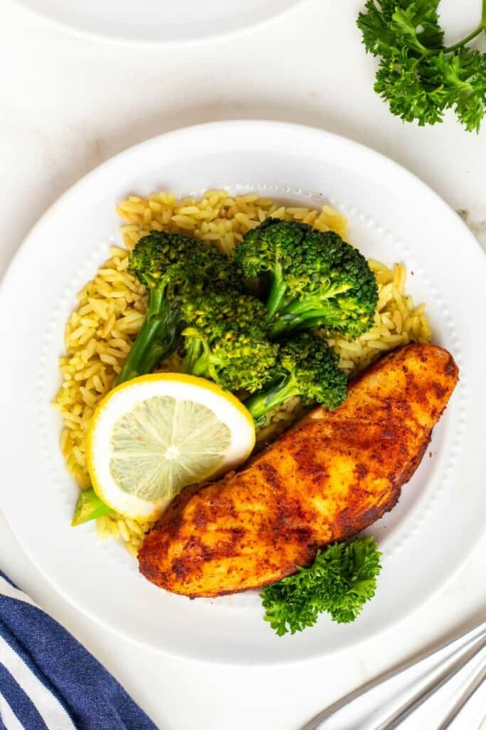 A plate of seasoned halibut with broccoli and lemon.