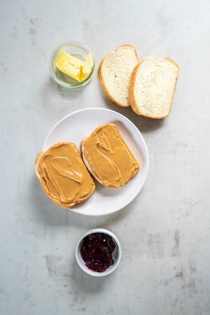 Peanut butter spread on two slices of bread resting on a white plate.