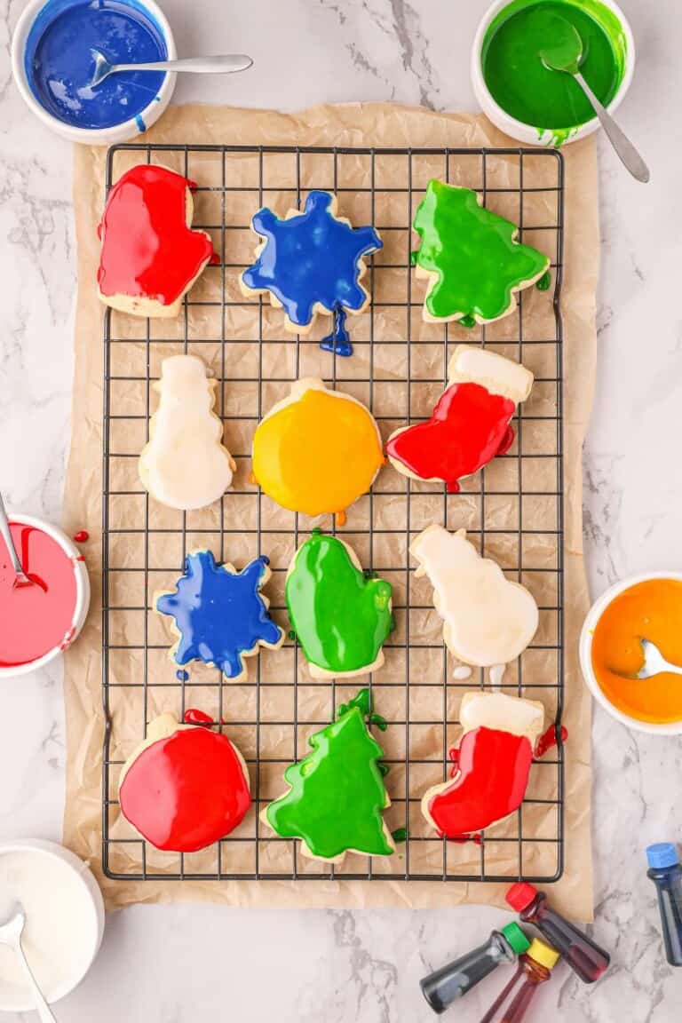 Twelve decorated christmas sugar cookies on a cooling rack.