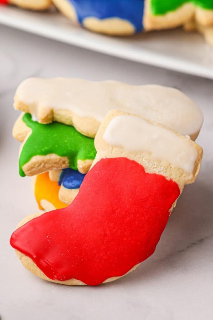Close up view of a Christmas Stocking decorated sugar cookie resting on additional decorated cookies.