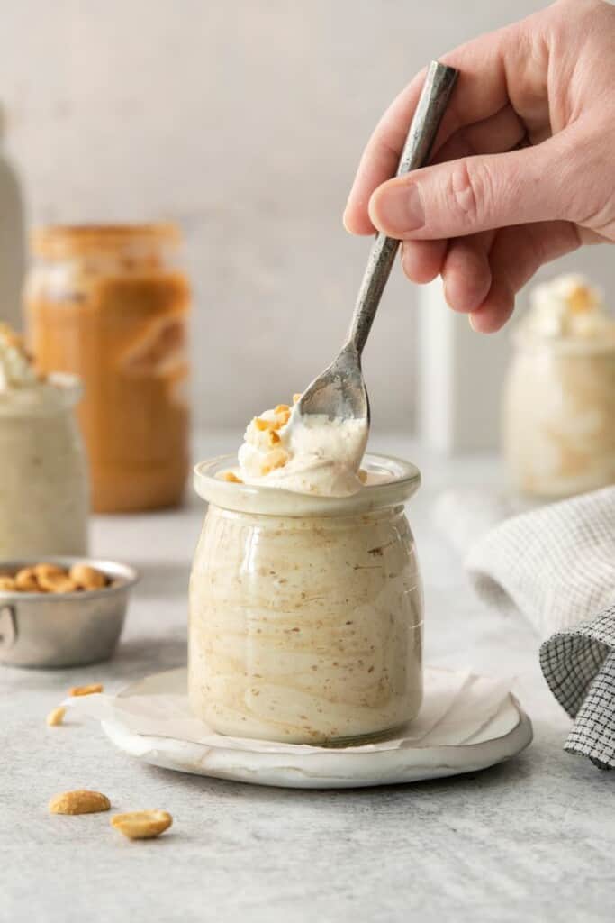 Dipping a spoon into whipped cream topped peanut butter mousse.