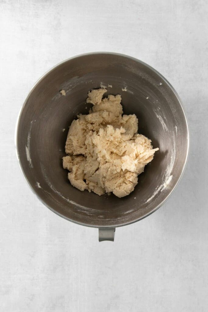 Adding flour to butter mixture in a mixing bowl.