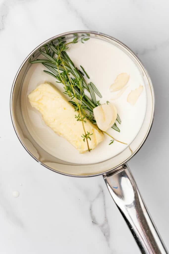 Cream, butter, garlic, rosemary and thyme in a saucepot.