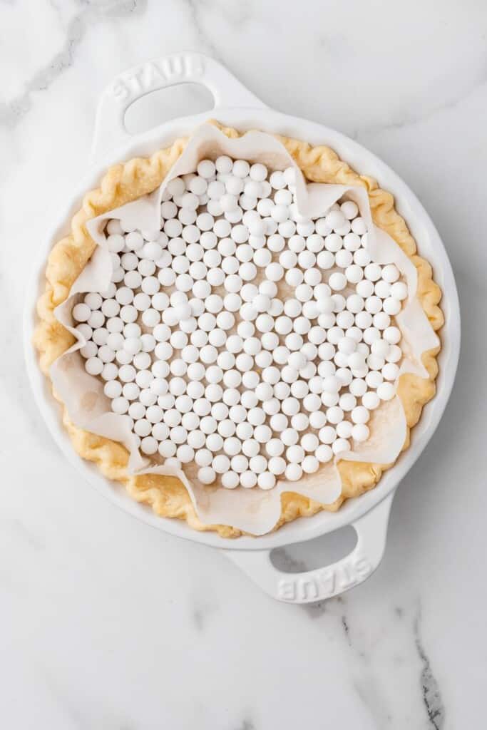 Pie weights on top of a parchment lined pie crust.