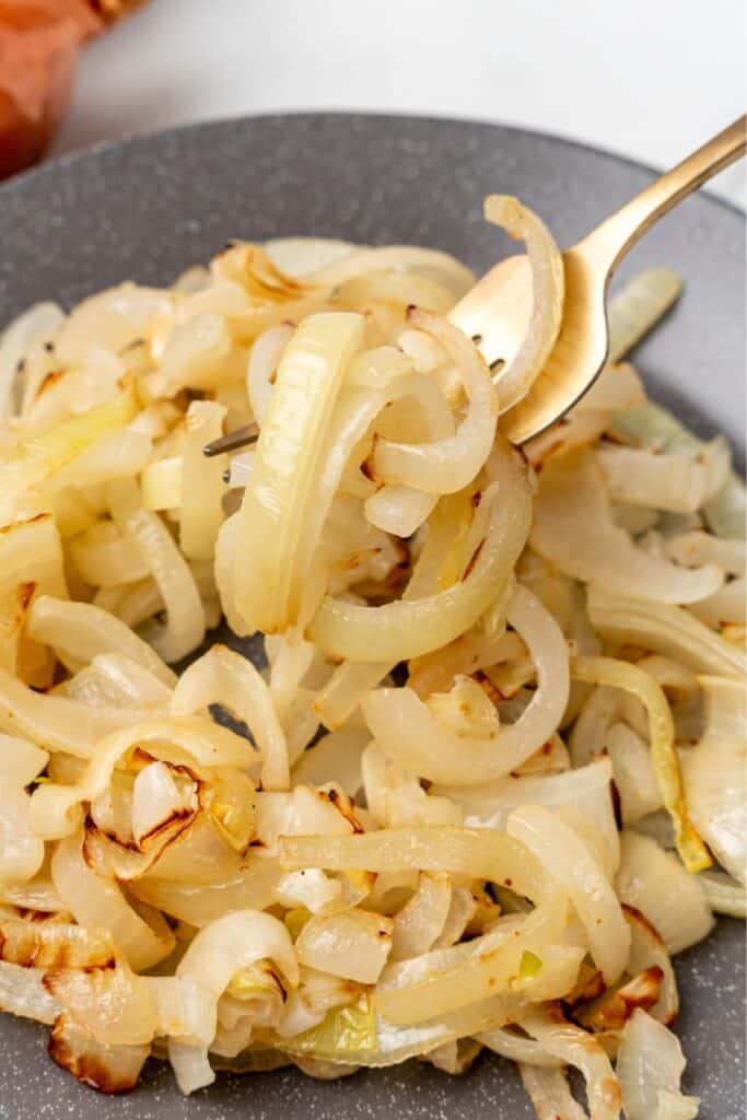 Air fryer onions on a plate with a fork in them.