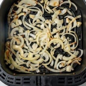 Air fried onions in an air fryer basket.