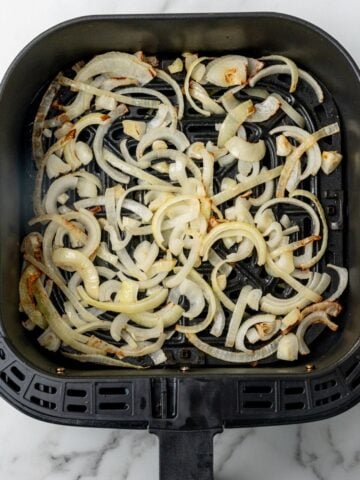 Air fried onions in an air fryer basket.