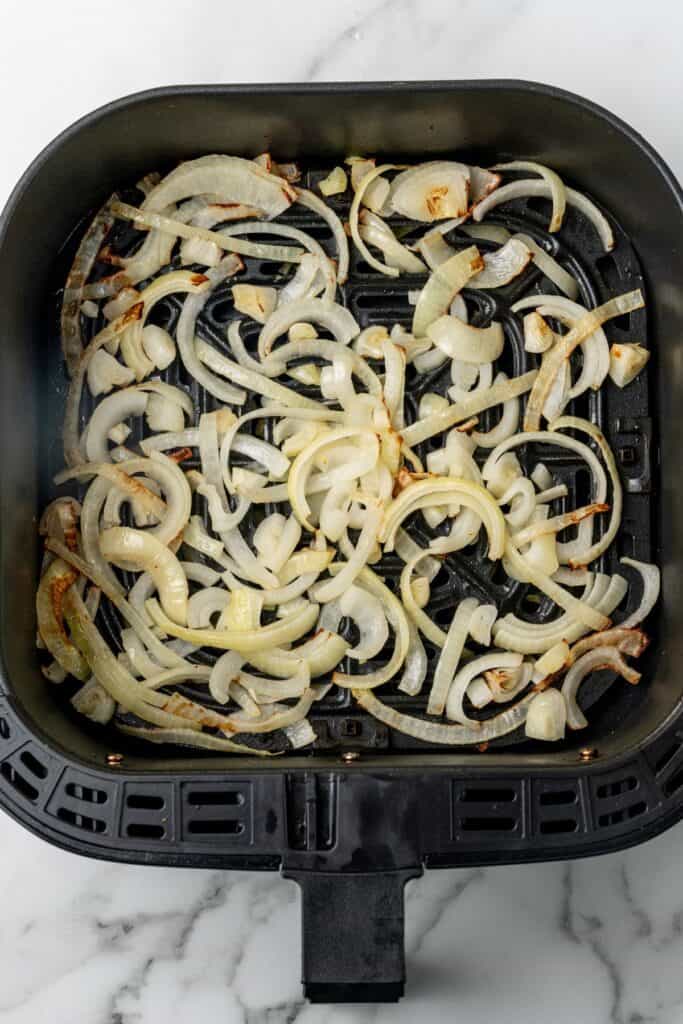Air fried onions in an air fryer basket.