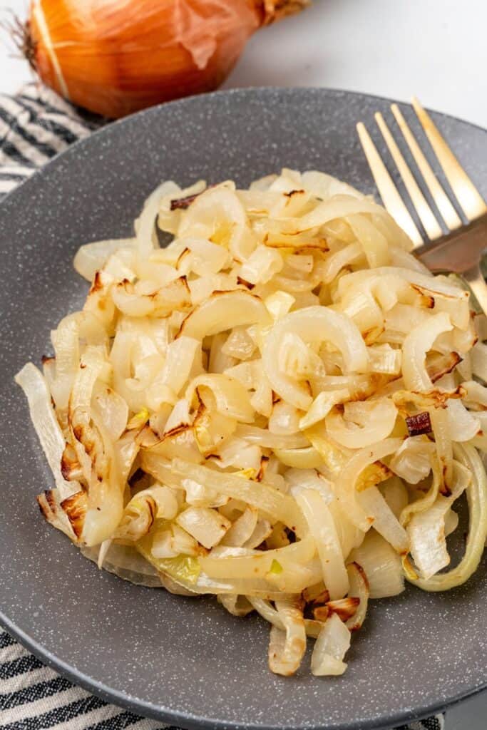 The air fryer onions on a grey plate with a fork next to it.