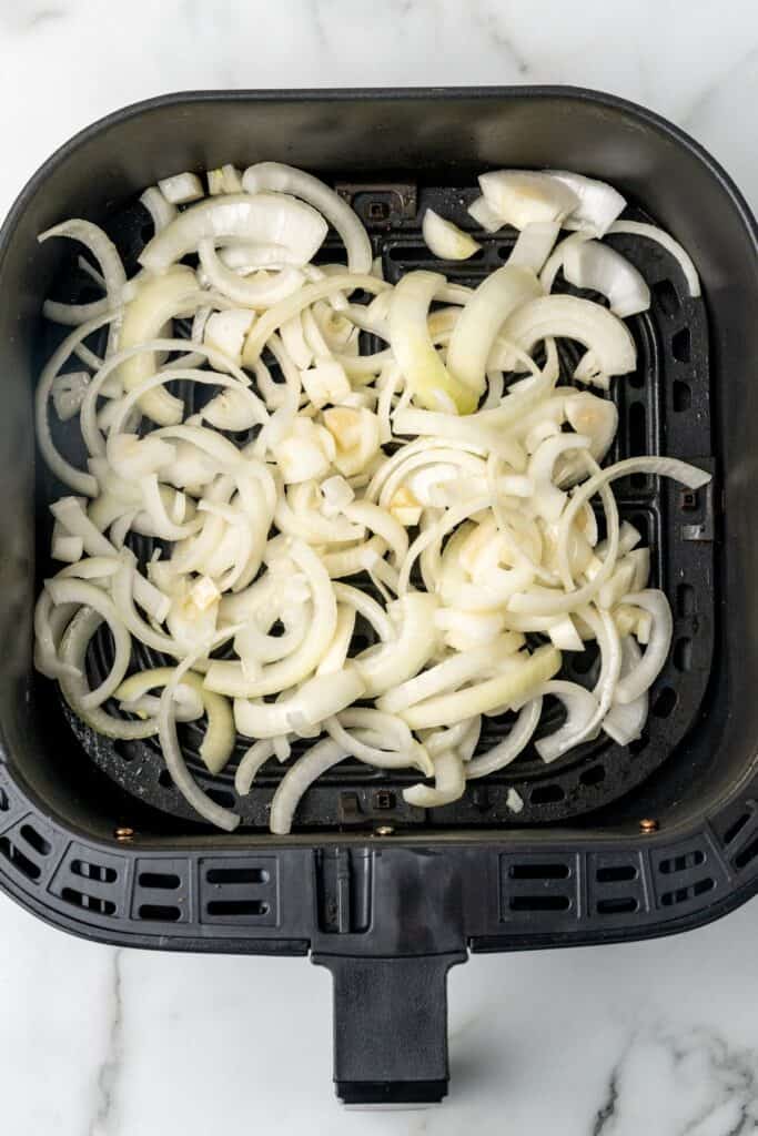 Raw onions in an air fryer about to be air fried.