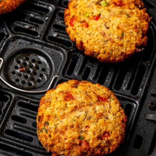 Close up of salmon patties in air fryer basket that are cooked.