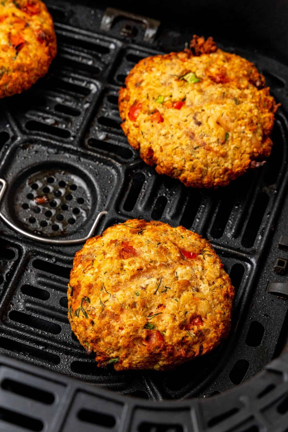 Close up of salmon patties in air fryer basket that are cooked.