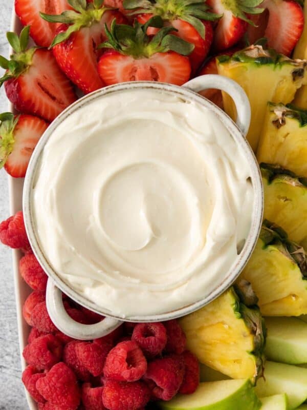 3 ingredient fruit dip with marshmallow fluff in a bowl with strawberries, apples, and pineapple chunks surrounding it.