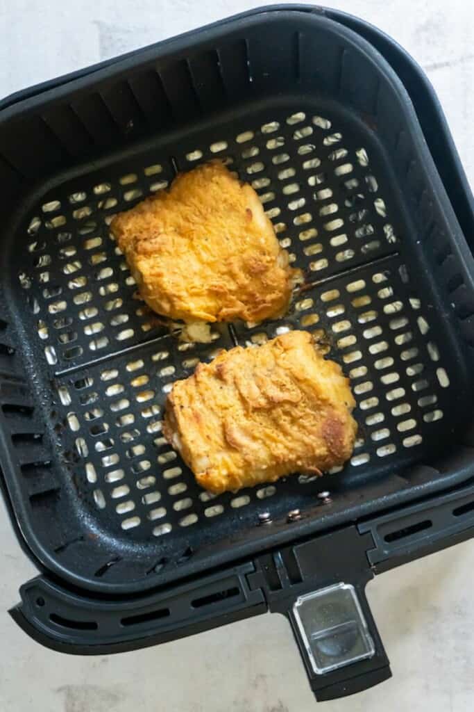 Fried fish in air fryer basket being reheated