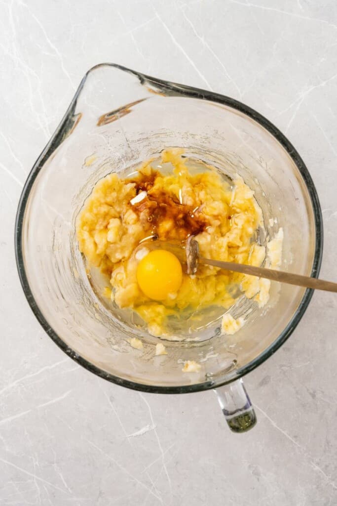 Combining bananas, egg, canola oil and vanilla extract in a mixing bowl.