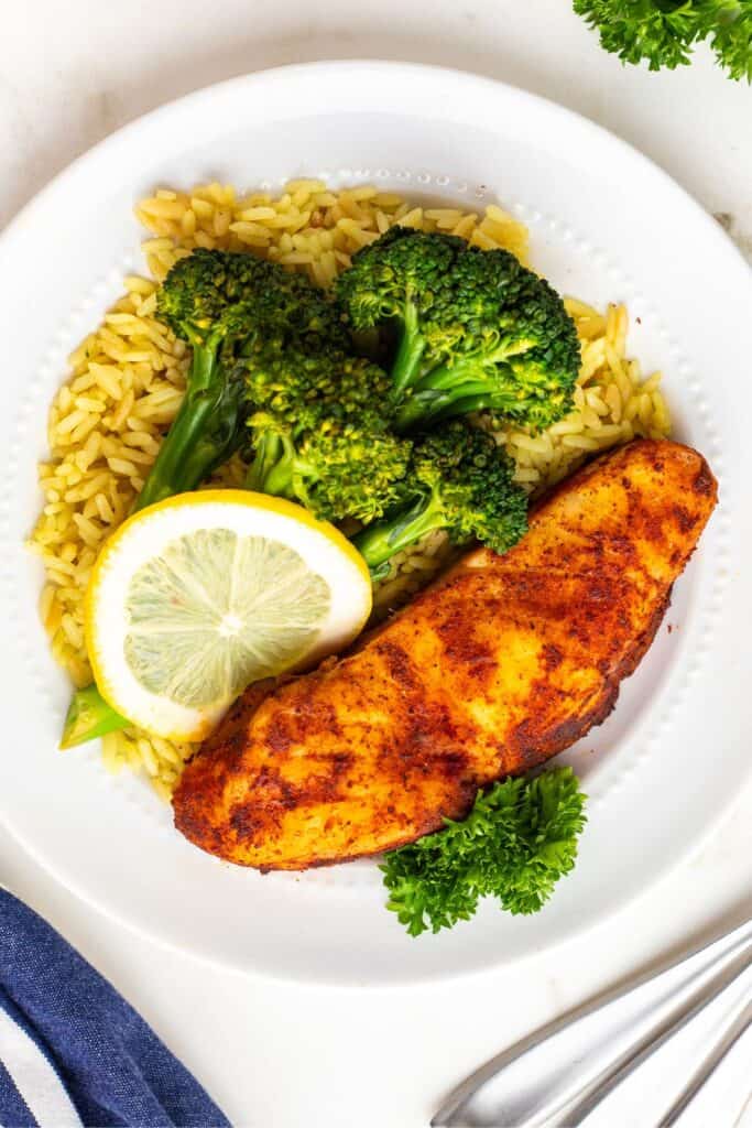 Air fryer halibut on a white plate with rice and broccoli