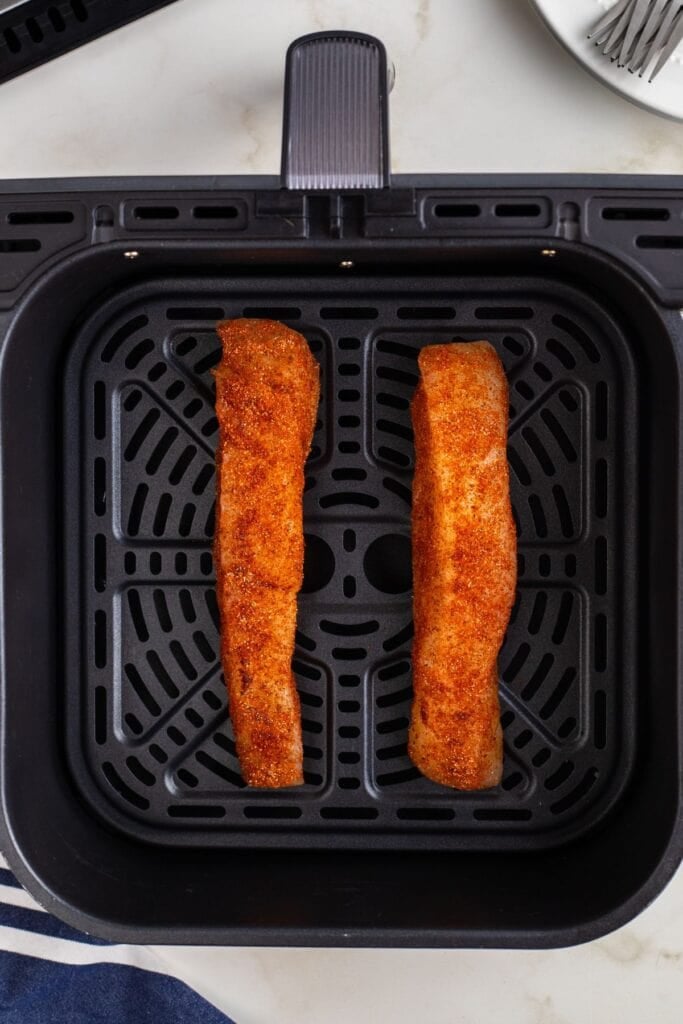 Raw halibut in an air fryer basket.