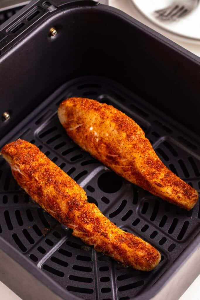 Close up of cooked halibut in an air fryer basket.